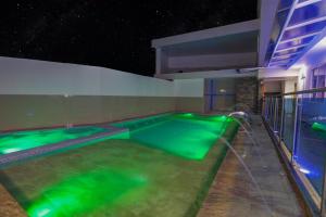 an indoor swimming pool with green water at night at Ocean Blue Beach in San Andrés