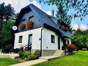 a white house with flower boxes on the roof at Plitvice Retreat Apartments in Rudanovac