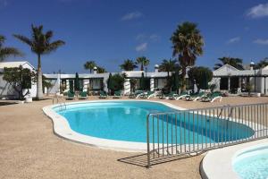 una grande piscina in un resort con palme di Bandama 14! 2 Bedroom Newly Renovated Bungalow, Los Pocillos, Puerto Del Carmen. a Puerto del Carmen