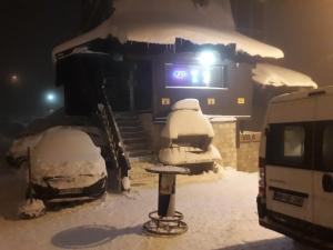 un camión cubierto de nieve frente a un edificio en Apartments Artic, en Jahorina
