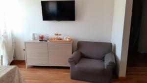 カンポバッソにあるB&B Apartament Umbria6の壁にテレビが付いた客室内のグレーの椅子