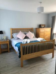 1 dormitorio con cama de madera y almohadas rosas en Littles Cottage, heart of the Mournes, en Annalong