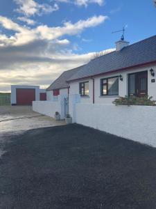 ein weißes Haus mit einer Einfahrt davor in der Unterkunft Littles Cottage, heart of the Mournes in Annalong