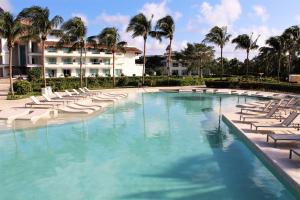a large swimming pool with lounge chairs and palm trees at BlueBay Grand Esmeralda-All Inclusive in Playa del Carmen