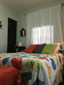 a bed with a colorful comforter and a window at The Jewel of Little Havana - 2S in Miami