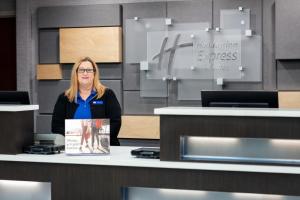 a woman standing behind a counter with a book at Holiday Inn Express & Suites Milton East I-10 by IHG in Milton +38 photos