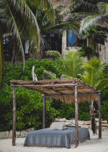 a bed with a thatched canopy on a beach at NEST Tulum in Tulum