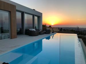 a house with a swimming pool with a sunset in the background at Villa Infinity Denia in Denia