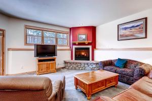 a living room with couches and a tv and a fireplace at Corral at Breckenridge #103E - Private Hot Tub - Close to Town in Breckenridge
