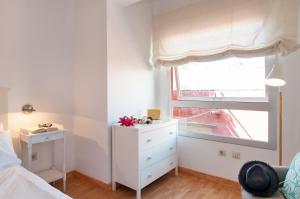 Flatguest Triana في لاس بالماس دي غران كاناريا: غرفة نوم بيضاء مع نافذة وخزانة بيضاء