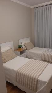 1 dormitorio con 2 camas y una ventana con cortinas en Excelente Sobrado Confortável no Centro de Tijucas Próximo as Praias, en Tijucas