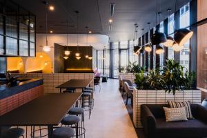 un restaurante con mesas, sillas y plantas en Abode Belconnen, en Canberra