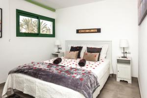 a white bedroom with a large bed with red flowers on it at Apartamentos los volcanes in Puerto del Carmen +53 photos