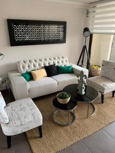 a living room with a white couch and two chairs at MATI´S APARTAMENT in Antofagasta