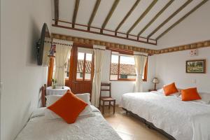 a bedroom with two beds with orange pillows at Hotel Villa del Angel in Villa de Leyva