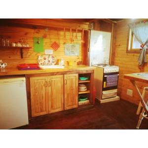 a small kitchen with wooden cabinets and a stove at El Canto de la Ballena Bungalow 2 niveles in Puerto Pirámides +9 photos