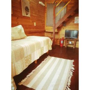 - une chambre avec un lit et une télévision dans une cabine dans l'établissement El Canto de la Ballena, à Puerto Pirámides