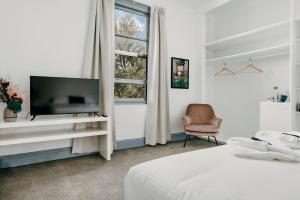ein Schlafzimmer mit einem Bett, einem TV und einem Stuhl in der Unterkunft The Victoria Hotel Bathurst in Bathurst