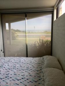 a bedroom with a large glass window with a bed at Max's Beachside Holiday Home in Torquay