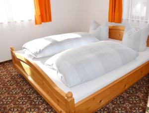 a bed with white sheets and pillows on it at Sonnenheim in Forchach