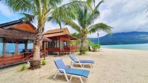 a house on a beach with two chairs on the sand at Lipe Beach Resort in Ko Lipe