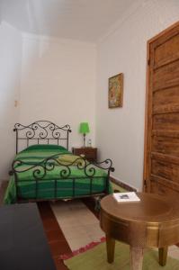 una camera da letto con un letto verde e un tavolo di Tanger Chez Habitant a Tangeri Altre 26 foto