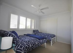 a bedroom with a bed and a couch and a fan at Island Time in Bongaree