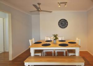 a dining room table with chairs and a clock on the wall at Island Time in Bongaree