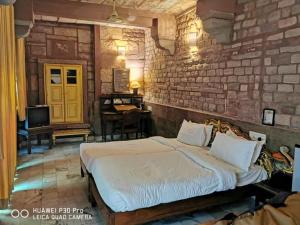 een slaapkamer met een bed en een bakstenen muur bij Krishna Prakash Heritage Haveli in Jodhpur