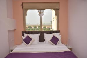 a bed with purple and white pillows in front of a window at Hotel Siddharsh Heritage in Jaipur