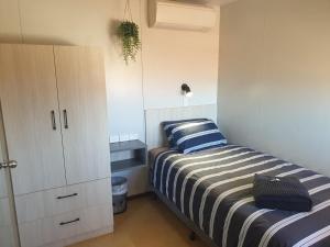 a small bedroom with a bed and a cabinet at Oasis Newman in Newman