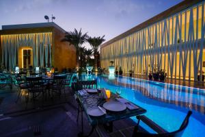 Vivienda Hotel Villas, Jeddah في جدة: مطعم بطاولات وكراسي بجانب مسبح