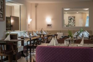Sandwirth Suites Palais Musil في كلاغنفورت: مطعم بطاولات وكراسي وطاولة قماش أرجوانية
