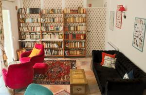 a living room with two chairs and a book shelf with books at Logis Hôtel La Villa Boucicaut in Chalon-sur-Saône