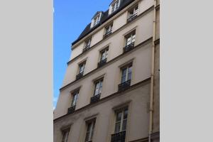 a tall white building with windows on the side of it at French typical apartment (opéra 5D) in Paris