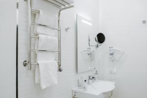 a white bathroom with a sink and a mirror at Adagio on Isaakiyevskaya in Saint Petersburg