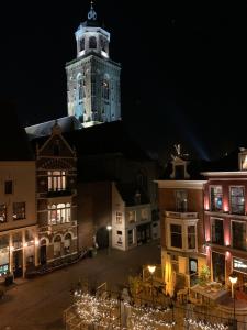 迪温特Kleinschalig Hostel in Deventer, centrum stad, aan de IJssel,的晚上有钟楼的大楼