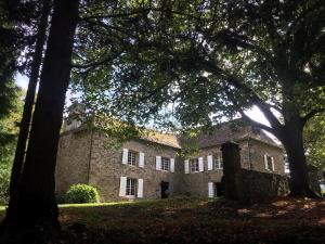 an old stone house with trees in front of it at Le Gîte du Château de Durfort in Soursac