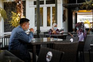 un hombre y una mujer sentados en una mesa en un restaurante en Oxville Hotel, en Padang