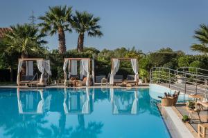 a pool at a hotel with chairs and palm trees at Avithos Resort Hotel in Svoronata