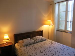 een slaapkamer met een bed met een lamp en een raam bij Au Relais de Nèche. in Bègues