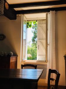 een eettafel en een raam met een deur bij Au Relais de Nèche. in Bègues