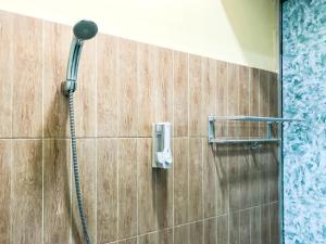 a shower with a shower head on a wall at Gangnam Hotel near Mall Olympic Garden Malang Mitra RedDoorz in Betek