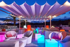
a hotel room filled with tables and umbrellas at Cala Llenya Resort Ibiza in Cala Llenya
