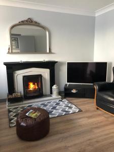 a living room with a fireplace and a leather couch at Littles Cottage, heart of the Mournes in Annalong