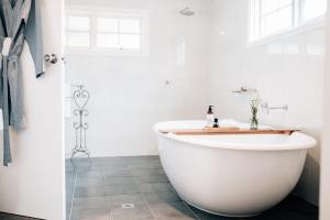 een badkamer met een wit bad en een wastafel bij Tomfoolery Winemaker's Cottage Barossa Valley in Lights Pass