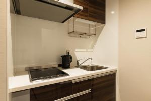 uma pequena cozinha com um lavatório e um fogão em GRAND BASE Hakata Naraya em Fukuoka