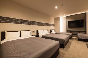 a hotel room with two beds and a flat screen tv at GRAND BASE Hakata Naraya in Fukuoka