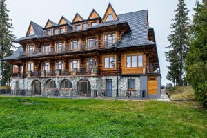 a large wooden house with a gambrel roof at Apartamenty na Leśnej in Bukowina Tatrzańska