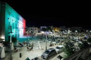 un grupo de autos estacionados en una plaza por la noche en Palazzo Introna en Mola di Bari